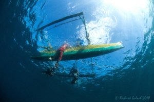 Lembeh-Local kids swimming next to father's canoe by Richard Goluch 